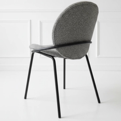 Silla Vila tapizada en tela boucle con patas de hierro negro.